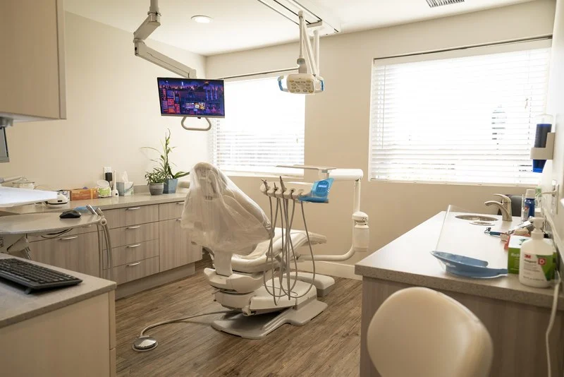 Treatment room with a dental chair and a ceiling-mounted TV